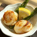 Two golden pan-seared scallops plated with asparagus and lemon