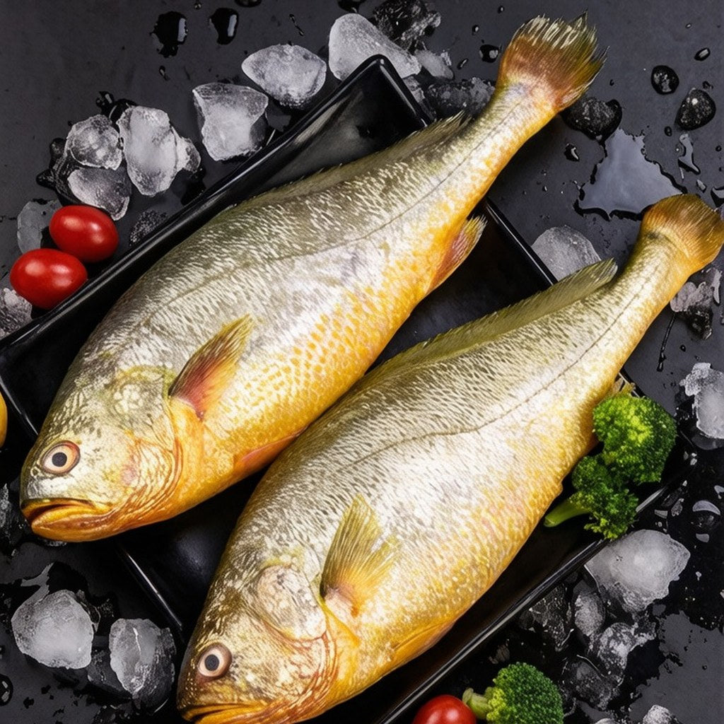 Two steamed whole croakers plated on dark slate with cherry tomatoes, herbs and ice
